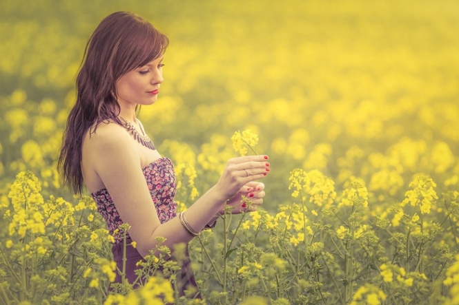Attractive genuine young girl enjoying the warm summer sun in a wide green and yellow meadow. Part of series.
