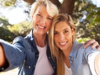 happy senior woman and daughter taking selfie together