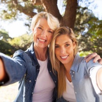 happy senior woman and daughter taking selfie together