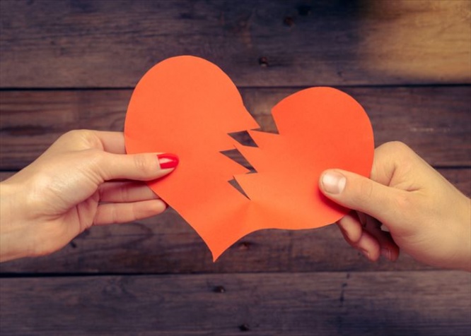 Male and female hands breaks red paper heart, concept of broken love
