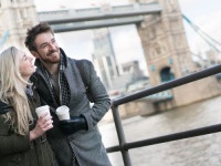 Happy couple on a date walking around London drinking a cup of coffee to go