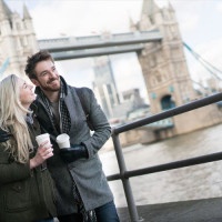 Happy couple on a date walking around London drinking a cup of coffee to go
