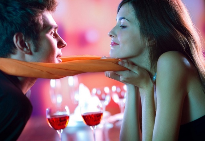 Young attractive happy couple kissing in restaurant, celebrating or on romantic date