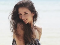 Beautiful toothy smiling woman joying on blue sea background