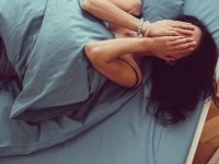 Depressed woman in bed with hands on face