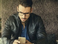 Handsome man with eyeglasses and leather jacket using smartphone