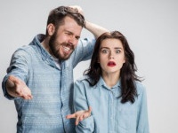 The young couple with different emotions during conflict on gray background