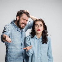 The young couple with different emotions during conflict on gray background