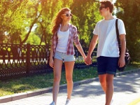 Summer, vacation, fun, relationships and people concept - pretty modern young couple in love walking in sunny summer day