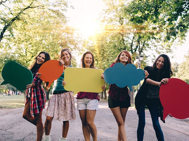 Happy friends with speech bubbles smiling to the camera