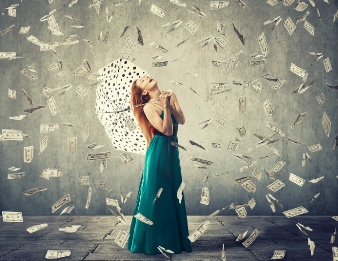 Happy woman with umbrella under a money rain