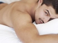 Handsome young man lying in his bed while shirtless