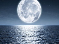 Full moon rising over empty ocean at night with copy space