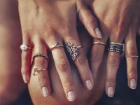 Cropped closeup of a boho girl's hands with many rings on her fingers, in gold and silver with dark blue stones