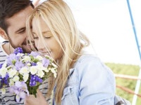 Loving couple riding Ferris wheel, woman holding flower bouquet