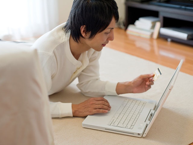 Man lying on his stomache and enjoying online shopping