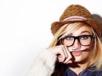 Closeup of a young woman holding her finger under her nose with a moustache drawn on it