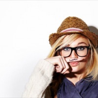 Closeup of a young woman holding her finger under her nose with a moustache drawn on it