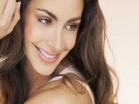 Happy beautiful young woman with long hair smiling over beige background. Fashion and beauty concept in studio.