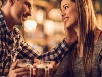 Loving young couple talking to each other in a bar and drinking beer in a pub.