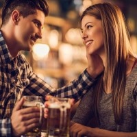 Loving young couple talking to each other in a bar and drinking beer in a pub.