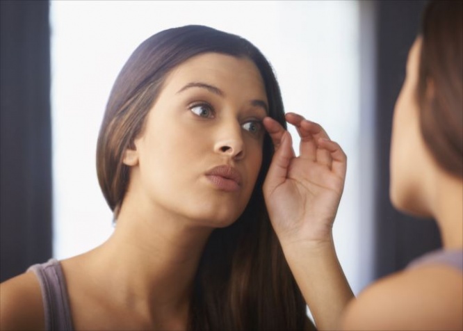 Shot of a woman looking at her appearance in the mirror