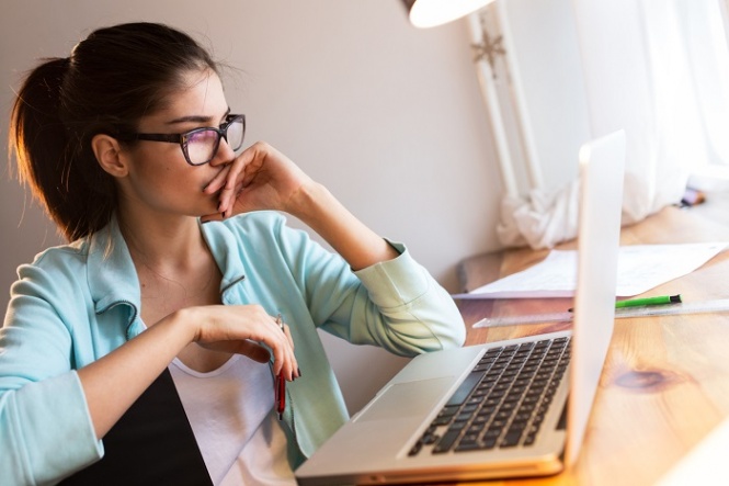 Young female blogger working at home.She sitting in her working room and typing something on laptop.Startup business.Looking worried.