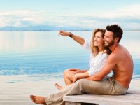 Smiling Couple sitting and pointing to the horizon