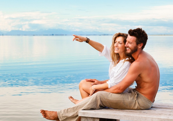 Smiling Couple sitting and pointing to the horizon