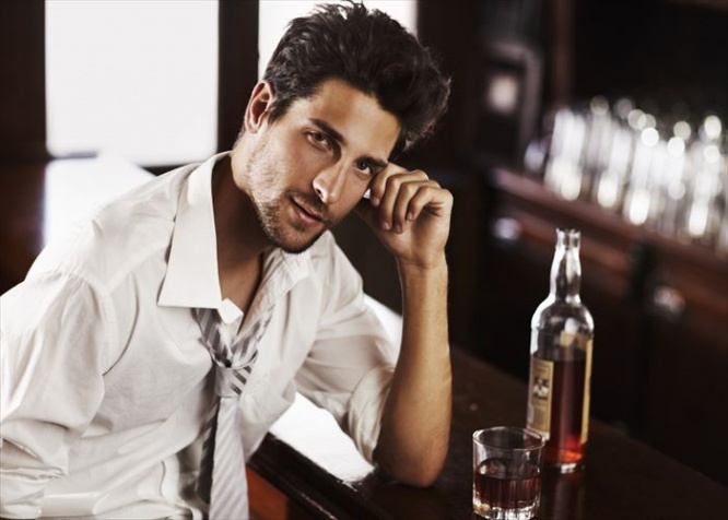 A handsome young man winding down after work with a drink at the bar