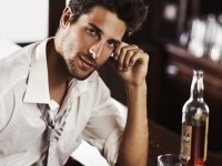A handsome young man winding down after work with a drink at the bar