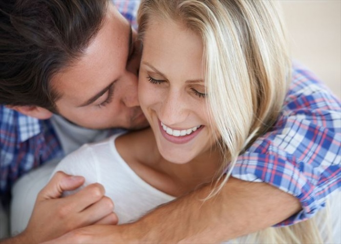 An affectionate man kissing his smiling girlfriends neck
