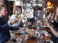 Group of friends toasting with white wine in restaurant