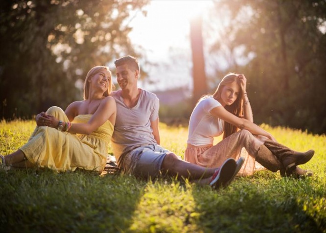 Happy couple talking to each other while young woman is depressed because the man didn't choose her.