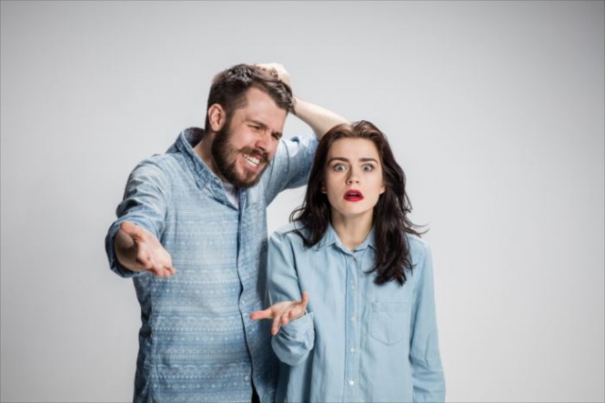 The young couple with different emotions during conflict on gray background