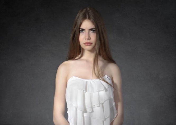Concept human emotions. Woman shows a grudge against a dark background