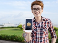 Vietnamese guy showing smiling emoji on the screen of his smartphone