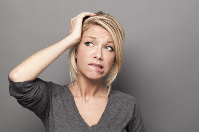 doubt and worry concept - anxious 20s cute blond woman expressing suspicion and anxiety with hand touching her head,gray background
