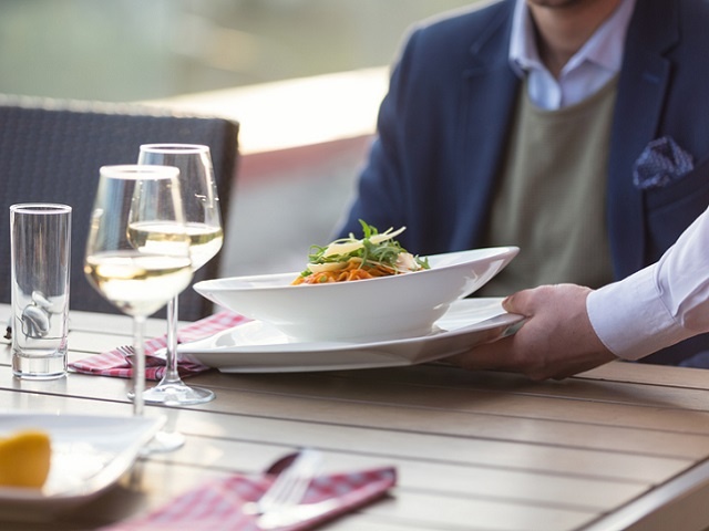 Waiter serving pasta in outdoor restaurant